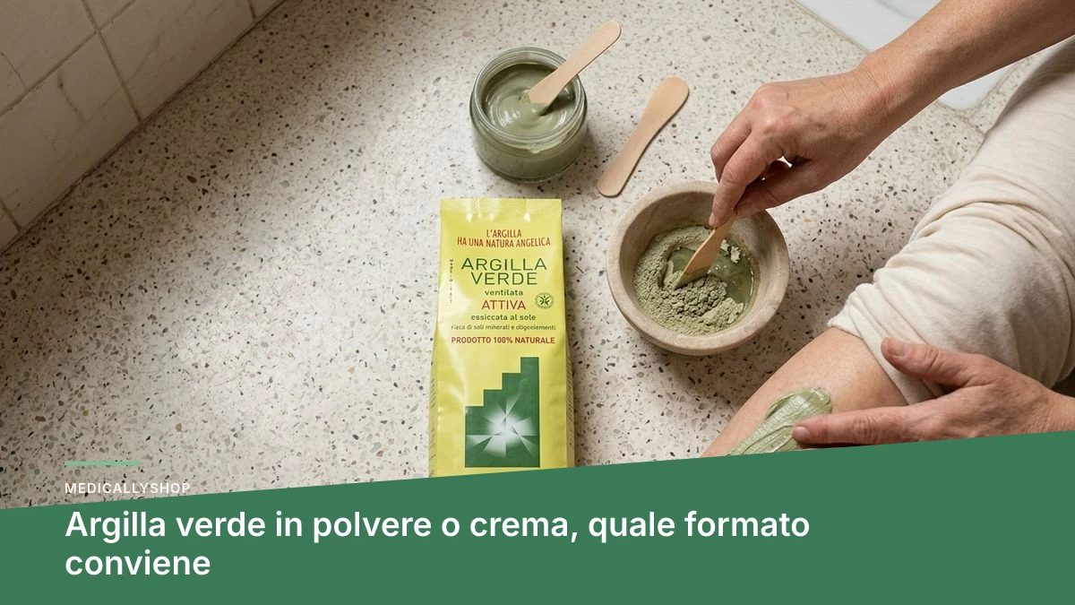 Ciotola in vetro con argilla verde in polvere e un cucchiaino di legno accanto a un vasetto di crema
